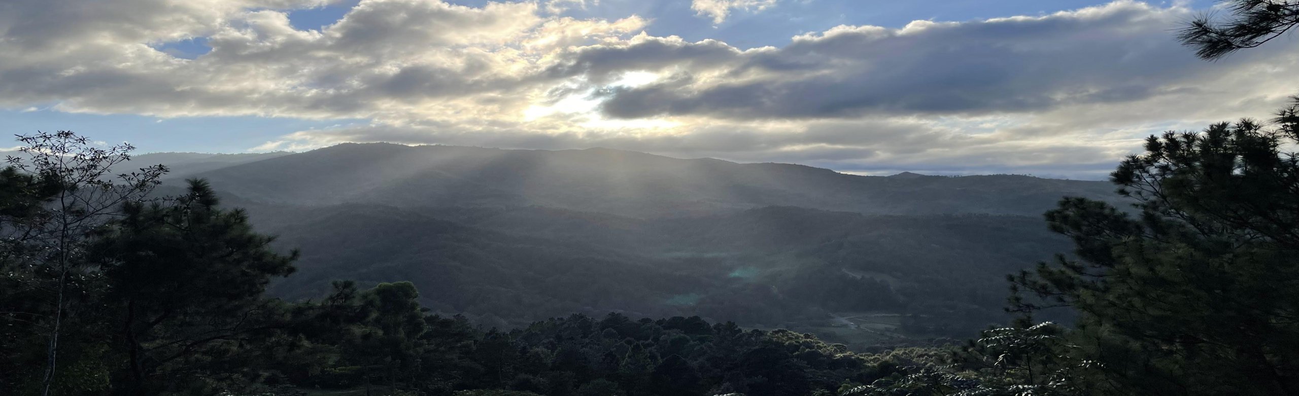 Sunlight breaking over layered mountain ridges in the Dominican highlands