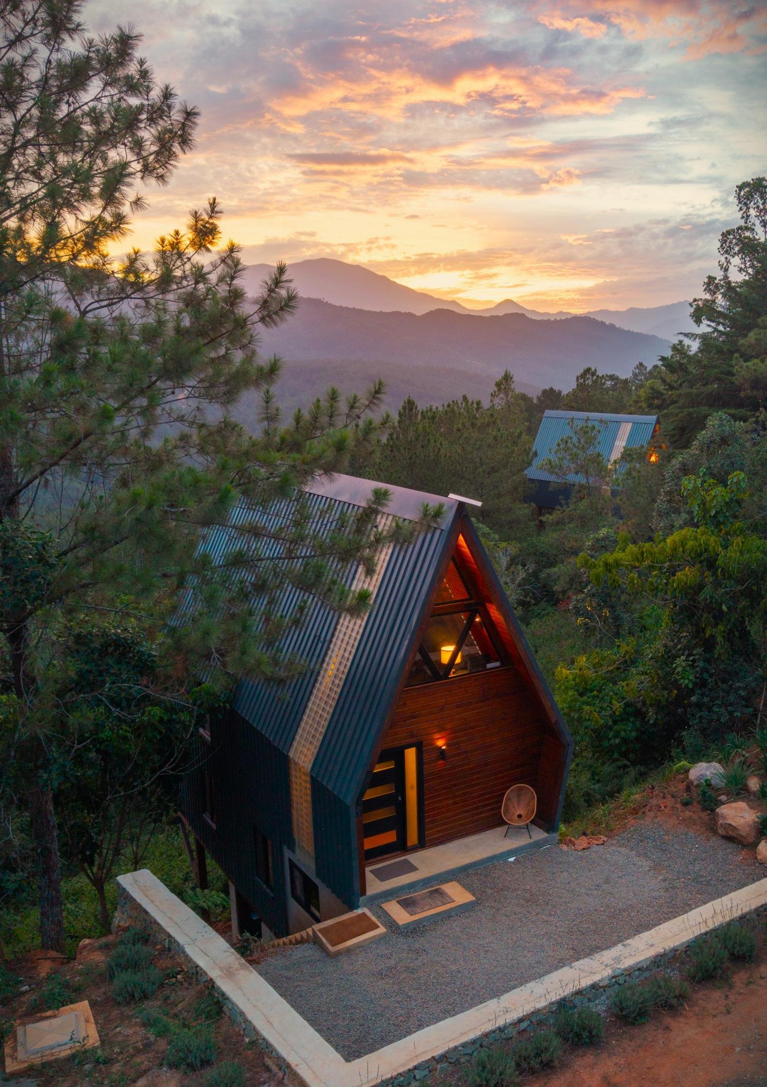 An A-Frame cabin and its gravel terrace beneath a mountain sunset